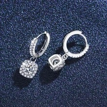 Macro shot of silver chain earrings with square-cut clear zircon pendants on blue backdrop