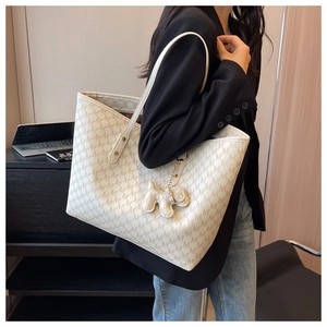 Close-up of beige monogram tote bag with brown letter print and cute puppy charm