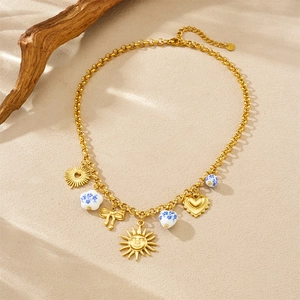 Detail of gold chain necklace featuring sun, bow, heart charms and blue floral beads