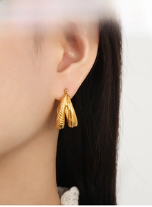 Close-up of model wearing gold U-shaped double hoop earrings with spiral texture design