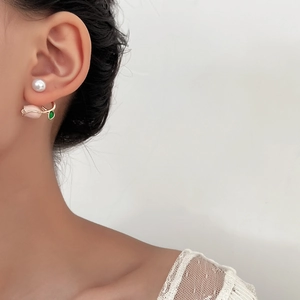 Nahaufnahme von rosa Blütenohrring und Perlenstecker am Ohr eines Modells
