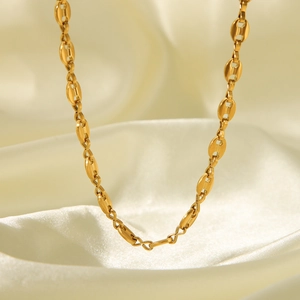 Elegant 18K gold-plated pig nose link chain necklace displayed on soft white silk fabric