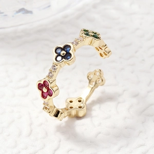 Adjustable gold ring with colorful clover-shaped gemstones in red, blue, and green