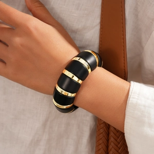 Close-up of chunky acrylic and metal bracelet with black and gold contrast on a wrist
