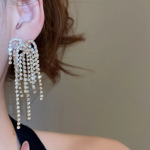 Detail of sparkling gold rhinestone tassel earrings worn by a model for elegant look