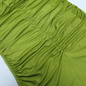 Close-up of green ruched milk silk fabric showing detailed texture and stitching