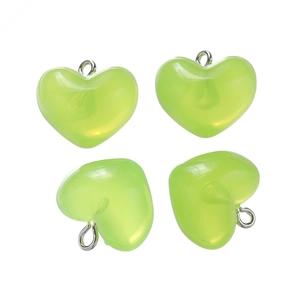 Macro shot of four translucent pale green heart charms with silver metal rings on white