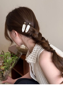Detail of cream drop hair clip with colorful rhinestones on a braided hairstyle