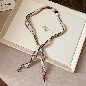 Detailed close-up of floral fabric choker with beads displayed on an elegant tray