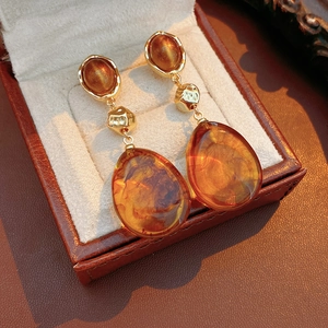 Close-up of amber resin drop earrings with golden hammered metal texture details