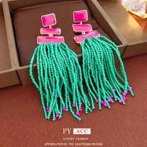 Exaggerated tassel earrings with pink metal inlay and vibrant green seed beads fringe
