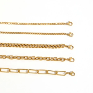 Assorted gold stainless steel chains in Figaro, Cuban and link styles on white background