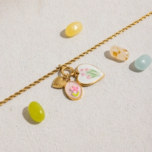 Détail du collier en acier titane doré avec pendentifs tulipe en émail et feuille