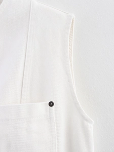 Detail view of white twill cotton vest featuring metallic rivet pockets and fine stitching