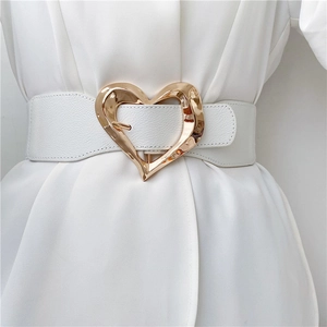 Close-up of a white leather wide waist belt featuring a golden heart-shaped buckle detail