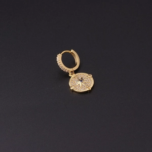 Detail of gold-plated earring with blue zircon star pendant on a textured dark background
