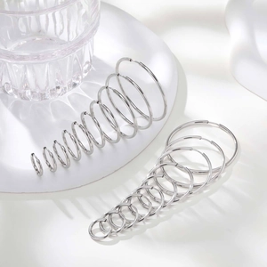 Detailed set of silver stainless steel hoop earrings in various sizes on minimalist white decor