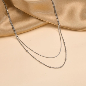 Detailed close-up of a silver double-layered snake chain necklace with small beads