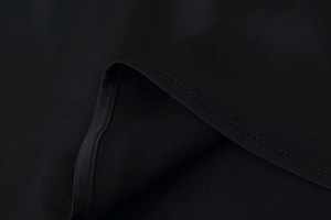 Close-up of the delicate lace stitching and satin fabric texture on the black dress