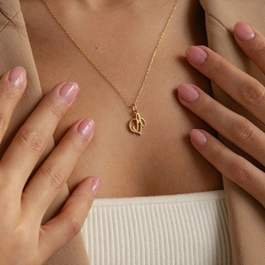 Close-up of a gold-plated snake chain necklace with a stylish letter pendant on model