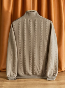 Dettaglio della maglia a trecce sul retro di un maglione beige con collo alto a zip