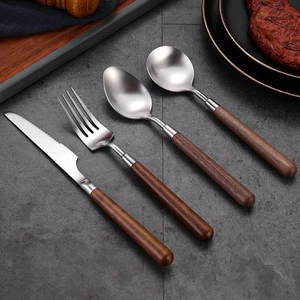 304 stainless steel cutlery set with walnut wood handles on a dark marble table