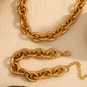 Gros plan d'un ensemble collier et bracelet à maillons épais plaqué or 18 carats sur beige