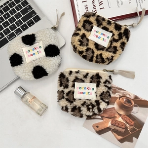 Plush makeup bags in polka dot and leopard prints arranged with lifestyle accessories