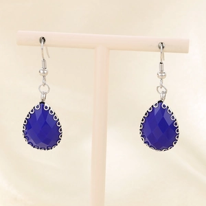 Détail de boucles d'oreilles en verre bleu facetté sur un support en métal argenté
