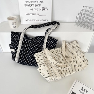 Detailed close-up of polka dot canvas tote bag with elegant white lace trim and straps