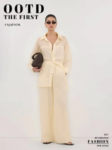 Detail view of pale yellow long-sleeve linen shirt and wide-leg trousers set with woven bag