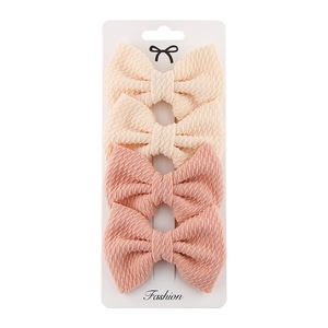 Detail of four-piece polyester bow hair clip set in cream and pink on display card