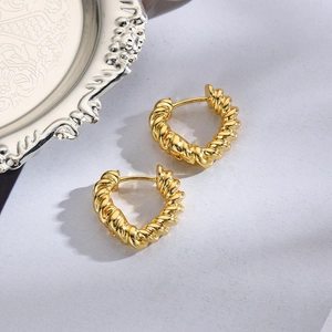 Close-up of golden twisted rope hoop earrings with a heart-shaped silhouette on a tray