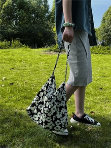 Outdoor shot of a black and white floral print cotton tote bag with a slouchy fit