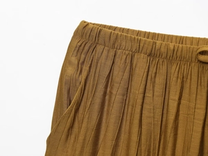 Detail of tan brown pleated midi skirt with elastic waist and side pockets texture