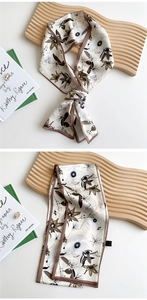 Detail view of a long narrow silk scarf with vintage floral prints and dark edge stitching