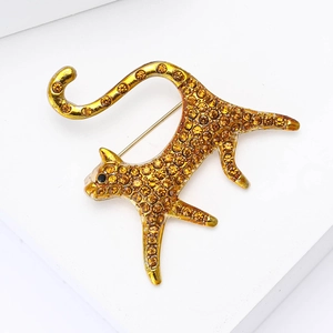 Detailed close-up of a gold leopard brooch with amber rhinestones and black gem eyes