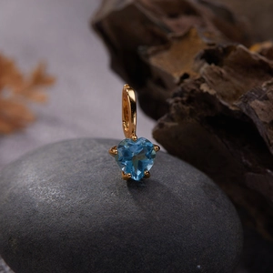 Macro shot of gold S925 silver pendant with heart blue gemstone on stone base