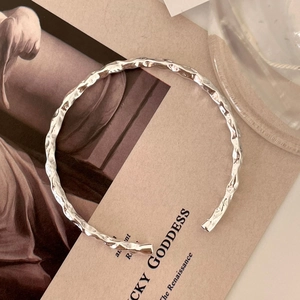 Minimalist 925 sterling silver open cuff bracelet with irregular hammered texture on art book