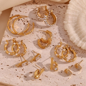 Detailed flat lay of 18K gold plated earrings with pearls and zircon on stone surface