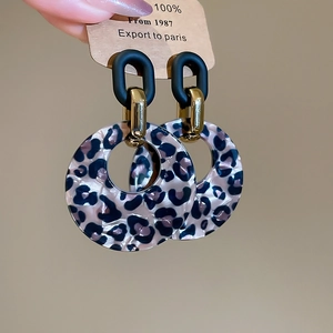 Detail of leopard print acrylic resin hoop earrings with gold links and vintage charms