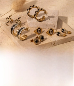 Detailed view of gold stainless steel snake earrings and zircon studs on marble stand