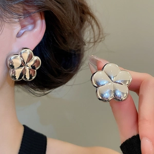 Detailed view of large silver five-petal flower stud earrings with a polished mirror finish