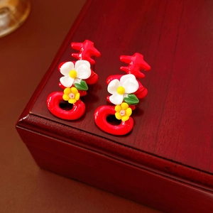 Close-up of red Double Happiness character earrings with small flowers on a wooden box
