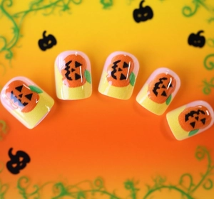 Detail of Halloween pumpkin nail patches with glossy finish and yellow-pink gradient