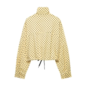 Detail of yellow polka dot jacket showing stand collar and black adjustable drawstring hem