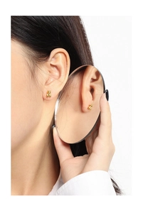 Creative model shot showing gold bear stud earrings reflected in a handheld mirror