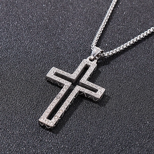 Macro shot of silver cross pendant with small diamonds on snake chain over black background