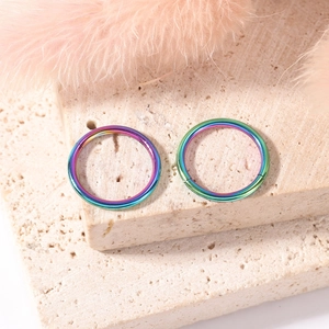 Macro shot of rainbow-plated stainless steel septum rings on a textured stone surface