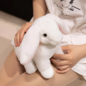Soft white plush rabbit doll with pink inner ears held by a model for size display